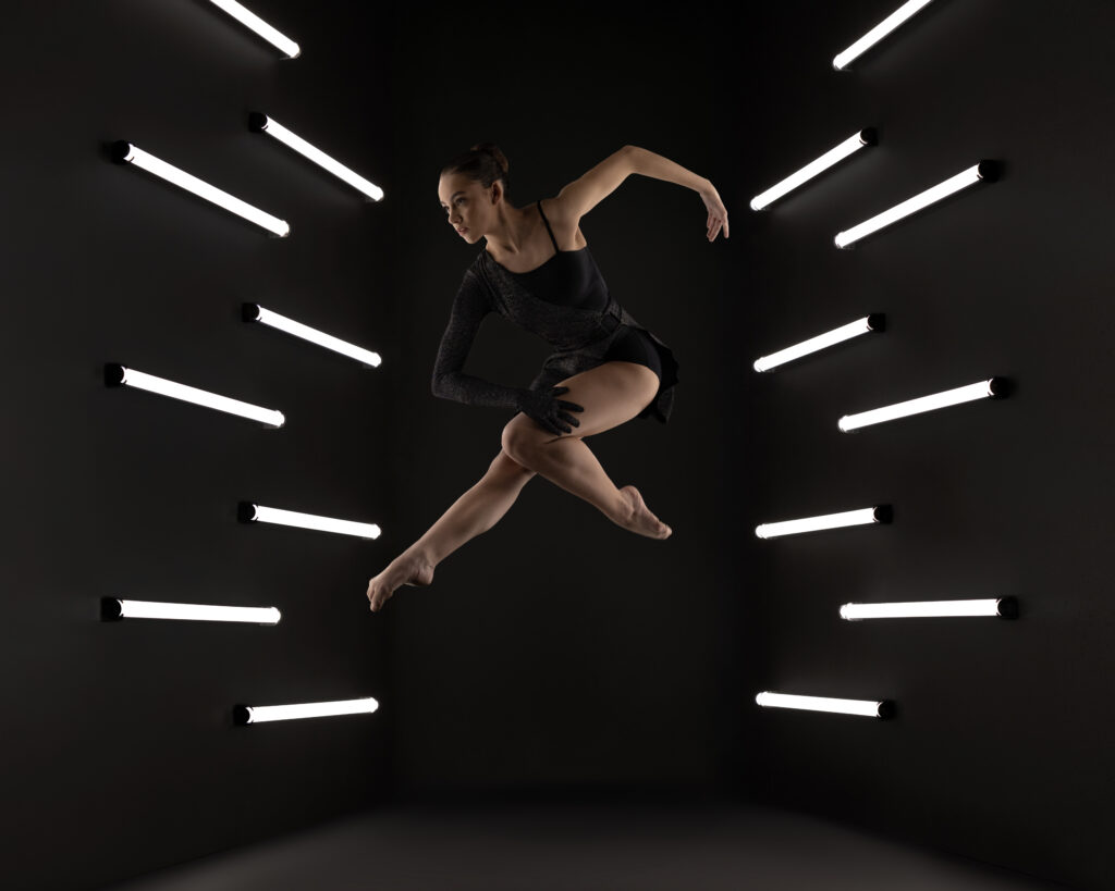 Dancer leaping in a studio lined with light tubes, commercial dance photography by Ashkan Image, Houston