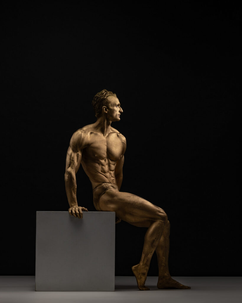 Houston fitness photography, athlete in gold body paint seated on a cube, by Ashkan Image