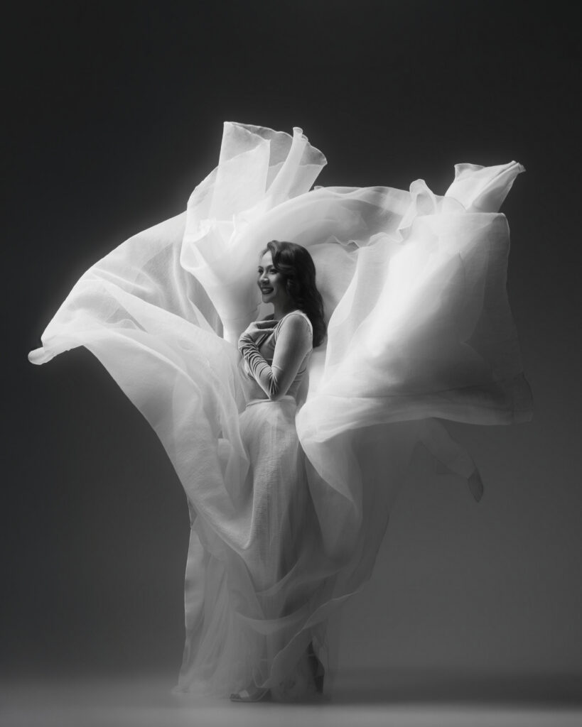Personal branding photography in Houston, woman smiling in a flowing white fabric gown, black and white, by Ashkan Image