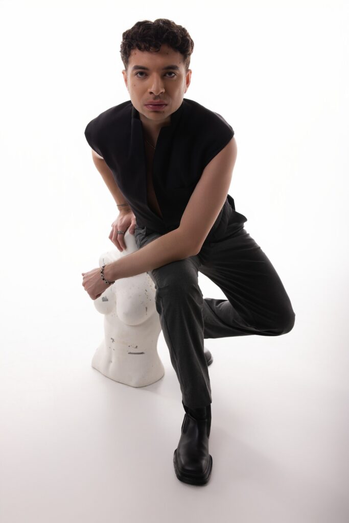 Personal branding photography in Houston, man in a black vest seated in a white studio, by Ashkan Image