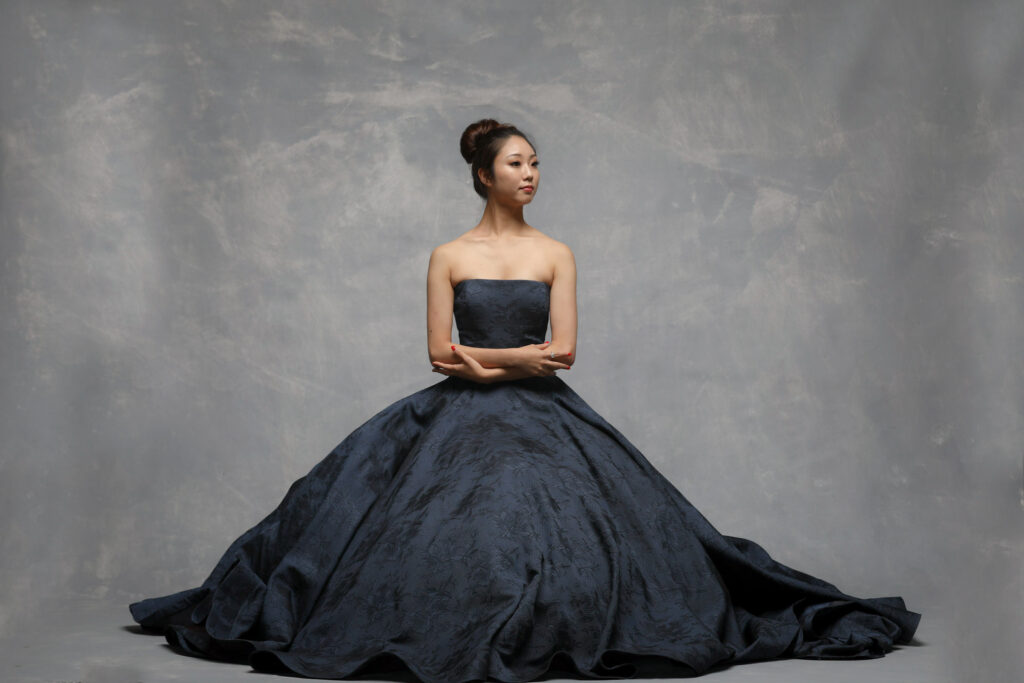 Personal branding photography in Houston, woman in a navy ball gown seated on a grey backdrop, by Ashkan Image